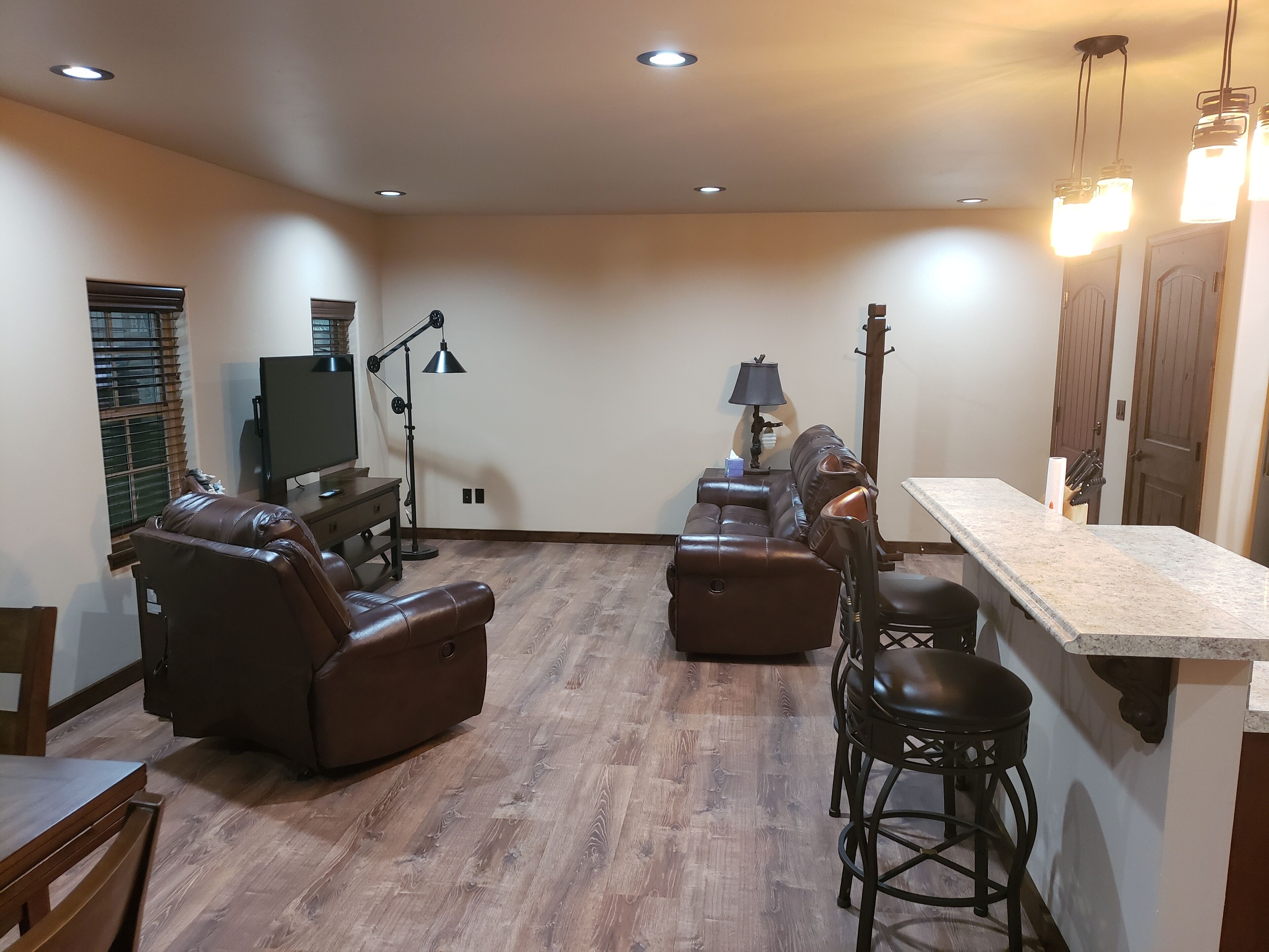 A spacious living room with a leather sofa, a TV, a lamp, and a bar area.