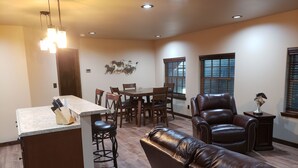 A spacious living area with a dining table, leather sofa, and a kitchen island with a knife block.