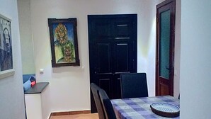 Un comedor con una mesa dispuesta para dos personas, una puerta oscura y un cuadro enmarcado en la pared.