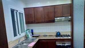 Una cocina con dos fregaderos, una estufa a gas y armarios de madera.