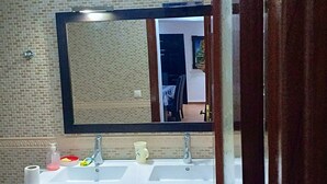 Un baño con un espejo grande, un lavamanos y un inodoro.