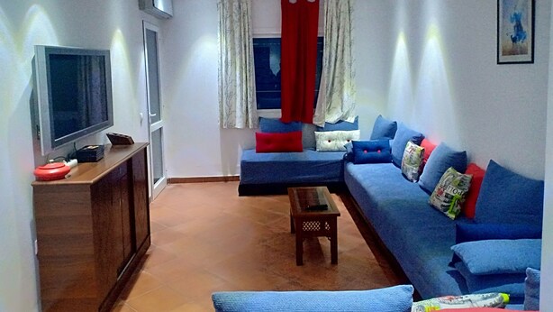 Una sala de estar con televisión, sofá y una mesita.