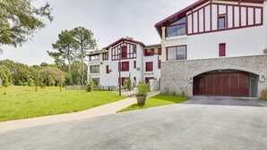 A two-story residential building with a red and white exterior, a driveway, and a well-maintained lawn.