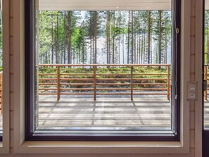 Eine Holzterrasse mit Metallgeländer, die zu einem bewaldeten Gebiet mit hohen Bäumen führt.