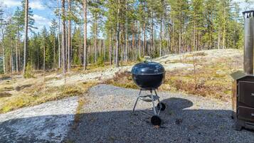 A portable grill set up on a gravel path in a forested area.