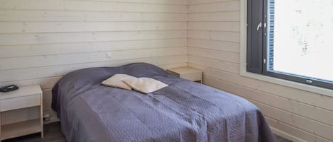 Une petite chambre avec un lit simple, une fenêtre, une table de chevet et une petite commode.