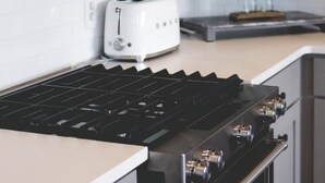 Une cuisine équipée d’une hotte en acier inoxydable, d’un grille-pain blanc et d’une plaque de cuisson noire.