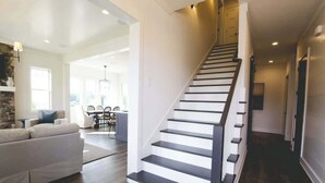 Un intérieur moderne comprenant un escalier, un espace de vie avec un canapé et un coin repas avec des chaises.