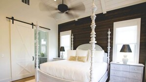 Une chambre à coucher avec un lit à baldaquin, une table de chevet, une commode et un ventilateur de plafond.