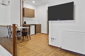 Eine moderne Küche mit Einbauofen, ein Essbereich mit Tisch und Stühlen sowie ein flachbildfernseher an der Wand.