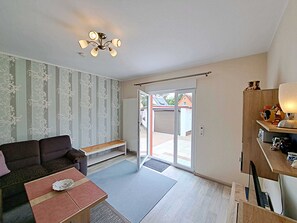 Een moderne woonkamer met een bank, een salontafel, een eettafel en een plafondventilator.