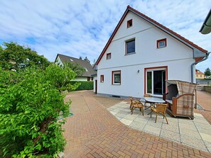 Een huis met twee verdiepingen en een patio met een tafel en stoelen.