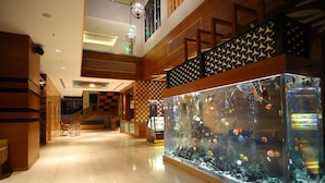 Eine geräumige Lobby mit einem großen Aquarium, einer Treppe und einem Empfangsbereich.