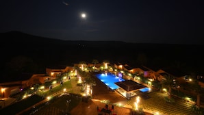 Ein Nachtbild eines Resorts mit Schwimmbad, Palmen und beleuchteten Wegen.