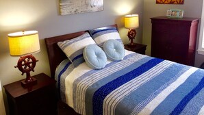 Een slaapkamer met een bed, twee nachtkastjes, een dressoir, een schilderij en twee lampen.