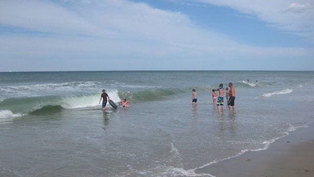 Een strand met mensen die deelnemen aan verschillende activiteiten in het water.