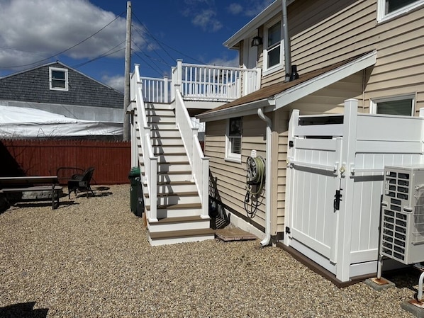 A residential property with a covered outdoor area, a wooden deck, and a white gate.