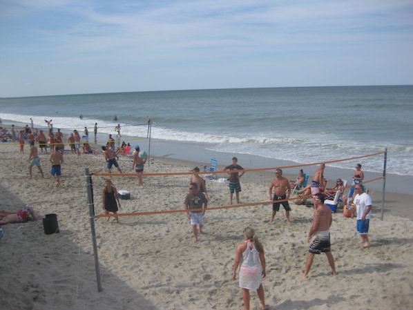 Een strandvolleybalwedstrijd op een zandstrand, met een net in het midden.