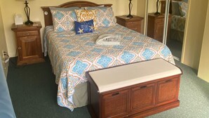 A bedroom with a bed, two nightstands, a ceiling fan, a mirror, and a window. - A Gem in the Hills - Your Secret Place From Home<br> (St. Thomas)
