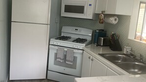 A compact kitchen with a refrigerator, microwave, stove, and sink. - A Gem in the Hills - Your Secret Place From Home<br> (St. Thomas)