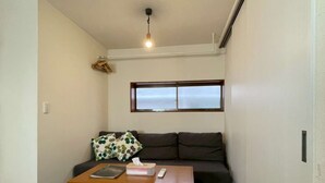 Un petit salon avec un canapé, une table et une fenêtre.