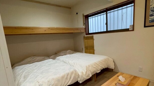 Una stanza compatta con un letto a castello, un piccolo tavolo in legno e una finestra con tende.
