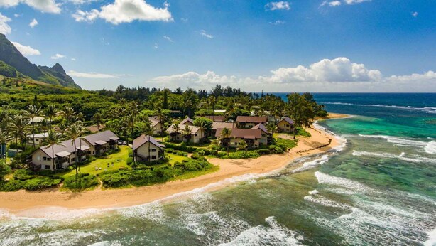 A coastal resort with multiple houses, a sandy beach, and clear blue waters.