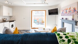 A modern living room with a sofa, a coffee table, and a TV mounted on the wall. - The Nook Close to Swansea Marina (Swansea)