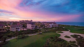 A coastal residential area with houses, a golf course, and a view of the ocean.