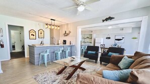 A spacious living area with a sofa, coffee table, and a kitchen in the background.