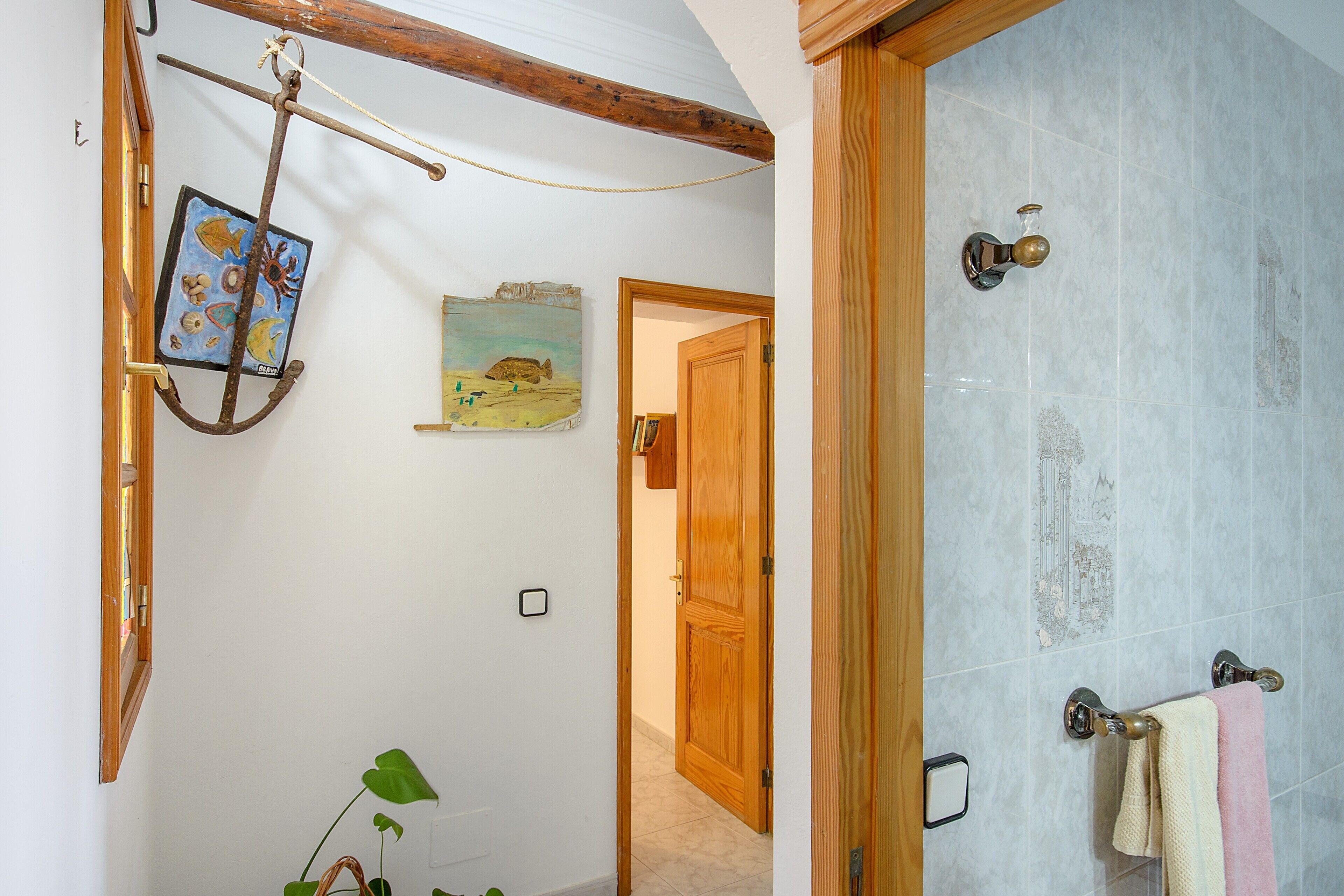 Une salle de bain avec une porte en bois, un porte-serviettes avec deux serviettes et un tableau accroché au mur.