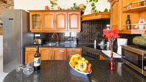 Een keuken met houten kastjes, een roestvrijstalen koelkast, een spoelbak en een fruitschaal op het aanrecht.