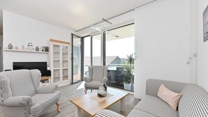 A modern living room with striped furniture, a flat-screen TV, and a glass door leading to a balcony. - Gloweglück, Germany (Glowe auf Rügen)