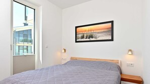 A bedroom with a bed, a window, a wall-mounted picture, and bedside lamps. - Gloweglück, Germany (Glowe auf Rügen)