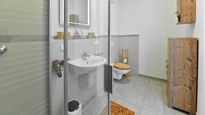 A modern bathroom with a glass shower enclosure, a white sink, a wooden toilet, and a wooden cabinet. - Gloweglück, Germany (Glowe auf Rügen)