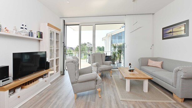 A modern living room with a flat-screen TV, striped armchairs, a sofa, and a wooden coffee table. - Gloweglück, Germany (Glowe auf Rügen)