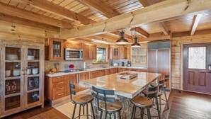 Una cocina amplia con armarios de madera, una isla central con taburetes y un refrigerador grande.