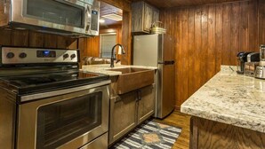 A kitchen with stainless steel appliances, wooden cabinets, and a marble countertop.