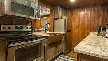 A kitchen with stainless steel appliances, wooden cabinets, a marble countertop, and a built-in oven.