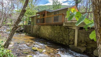 Un bâtiment aux murs de pierre, doté d’un balcon en bois qui surplombe un ruisseau.