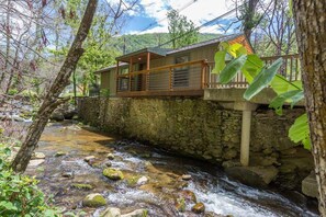 Un bâtiment aux murs de pierre, doté d’un balcon en bois qui surplombe un ruisseau.