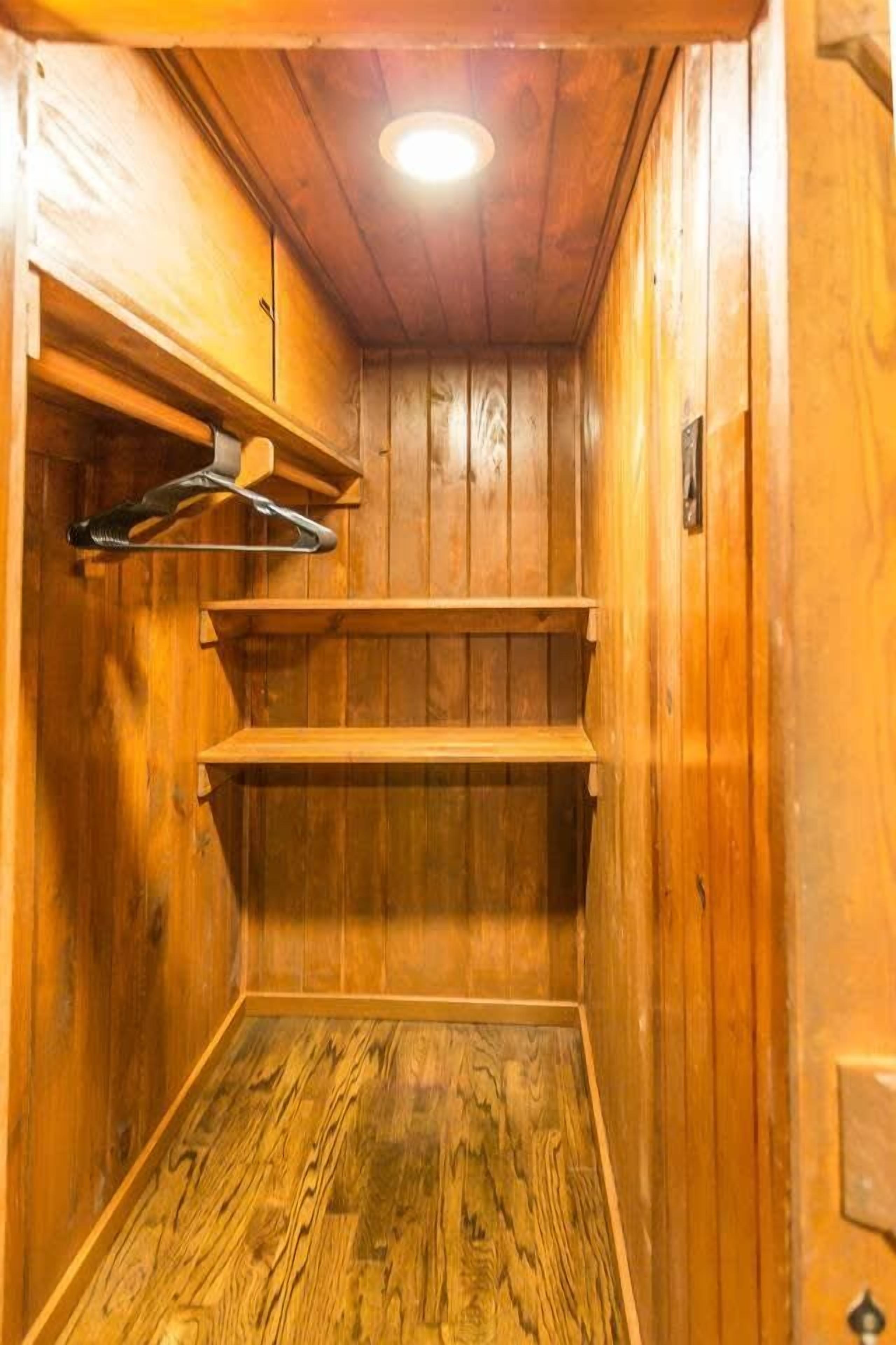 Een houten sauna met een bank, planken en een ophangrek.