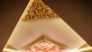 A hotel room with a large bed, a TV mounted on the wall, a chandelier, and a patterned carpet. - Can Deluxe Hotel (Alasehir)