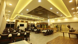 A spacious restaurant with multiple dining areas, a central bar, and a modern ceiling design. - Can Deluxe Hotel (Alasehir)