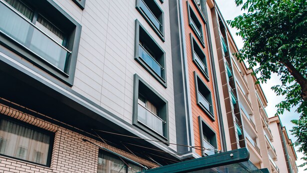 A hotel entrance with a red carpet, glass doors, and a covered walkway. - Can Deluxe Hotel (Alasehir)