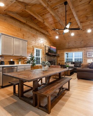 Una cocina amplia con armarios de madera, una gran mesa de comedor y una chimenea de piedra.