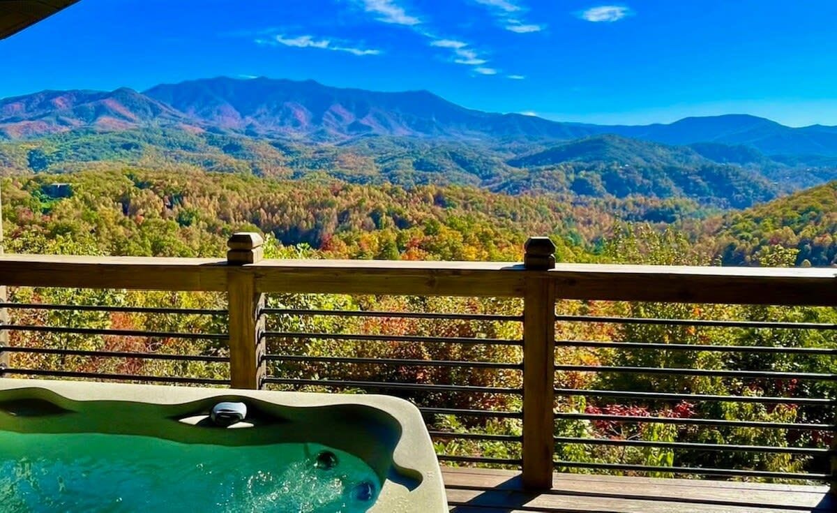 A hot tub on a wooden deck with a view of a mountainous landscape.