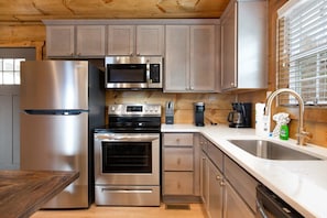 A modern kitchen with stainless steel appliances, wooden cabinets, and a large window.