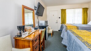 A hotel room with a desk, chair, bed, and a television mounted on the wall. - Parkway Inn (Waynesville)