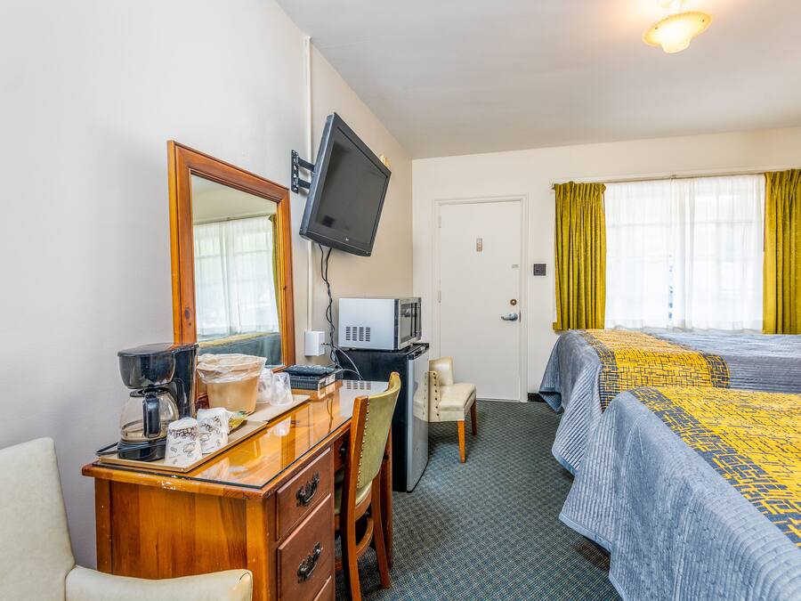Une chambre d’hôtel équipée d’un bureau, d’une chaise, d’un lit et d’un téléviseur fixé au mur.